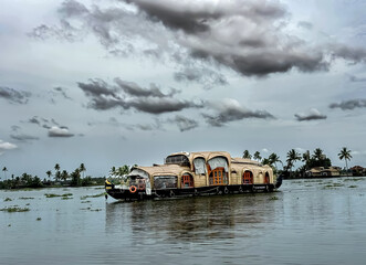 A charming Alappuzha houseboat, nestled on the serene backwaters of Kerala, features a traditional design with a thatched roof and a sturdy wooden hull.