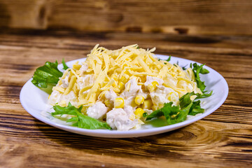 Festive salad with chicken breast, canned pineapple, cheese, sweet corn and mayonnaise on wooden table