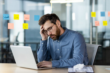 Stressed office worker sitting at desk with laptop feeling burnout