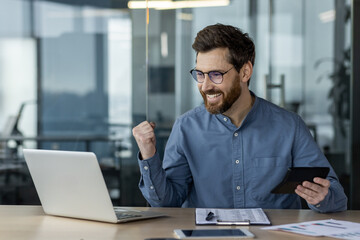 Happy financier working on laptop using calculator and phone in modern office