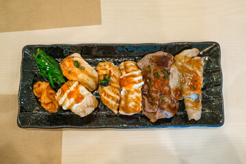 Ceramic tray with variety of sushi salmon, seafood roll and grilled beef appetizing meal