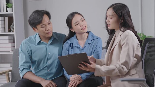 Business consultant discusses financial strategies with a young couple in an office. The couple listens attentively and asks questions