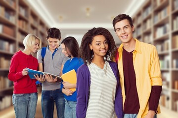 Happy young students in library with books