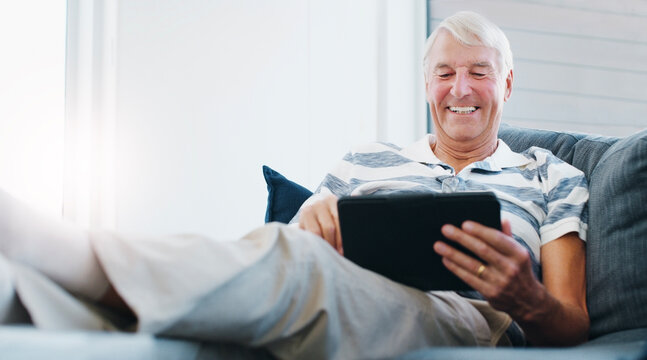 Senior man, tablet and retirement home with elderly dating site or puzzle app on sofa. Online, tech and living room with internet scroll and web search for social media setup advice with smile - Powered by Adobe