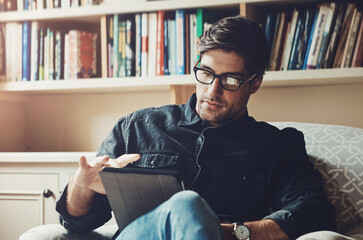 Reading, relax and tablet with man on sofa in living room of home for break, comfort or weekend time off. Ebook, glasses and technology with person chilling in apartment for peace, leisure or rest