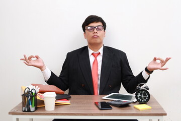 Attractive Asian Businessman in his office in zen position. Isolated on white