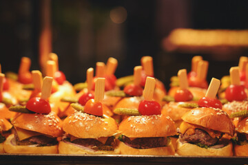 Mini hamburger snacks for dinner on a tray in a hotel buffet. Junk food concept.