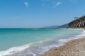 Beautiful coastal view of a bridge extending over the clear blue waters and sandy shore in a serene seaside location.