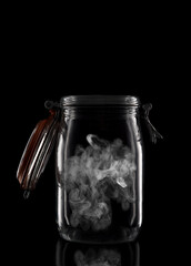 A glass storage or canning jar isolated on black with reflection, with lid open.