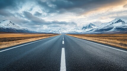 Naklejka premium Empty asphalt road leading towards majestic snow mountains and a cloudy sky, ideal for car journey themes.