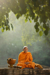 Asian monk meditating under a tree