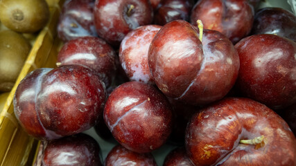 Pile of fresh plums in container at the supermarket. Abstract food fruit and vegetables texture.