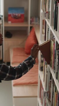 Dark-skinned guy scans shelf for book. African American student makes selections for individual task in university library. Man explores offerings in bookstore