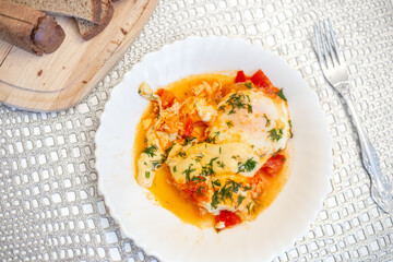 Israeli dish Shakshuka. Eggs with tomatoes on a white plate