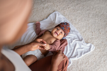 Anonymous woman changing clothes to her baby