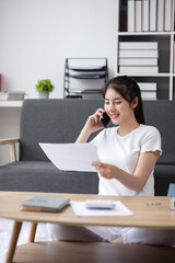 Woman Planning Finances for Buying a House While Sitting on the Floor and Talking on the Phone in a Modern Living Room