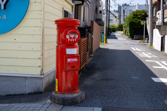 Ein roter Briefkasten der Japan Post Co., Ltd. ist deutlich sichtbar. Der Briefkasten tr&auml;gt das Symbol der Japan Post Services.