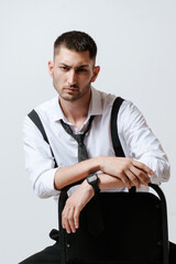 A man with white shirt and tie sits on a chair in studio. Barefoot