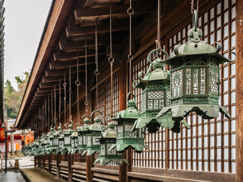 A row of traditional green iron lanterns hanging from a wooden temple