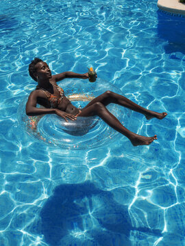 Black woman enjoying floating on water donut in pool