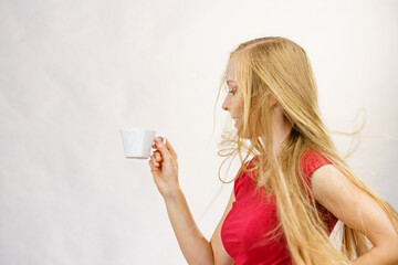 Blonde girl blowing hair holds coffee cup