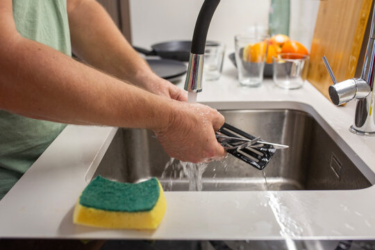 housekeeper Man Washing The Dishes on minimalistic kitchen.