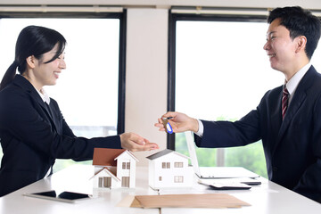 男性会社員が不動産の鍵を手渡すイメージ