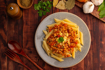 Penne macaroni with Meat Sauce,Easy Penne pasta tossed with a simple tomato sauce with ground beef and pork topped with cheddar cheese in a plate.Top view.