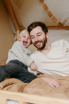 Dad and son cuddling in playhouse bed