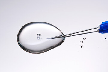 A drop of medicine flowing from a syringe with a needle.