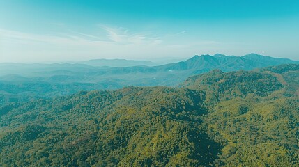 Naklejka premium Expansive Aerial View of Lush Green Mountains Under Clear Blue Sky in Early Morning