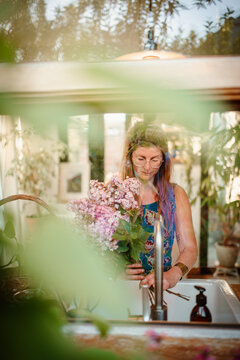 window portrait of a woman holding lilacs 