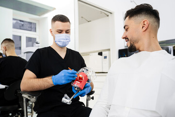 Teeth cleaning technique demonstration by dentist. Doctor teaches patient how to clean his teeth in...
