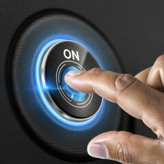 A person's fingers pointing towards a luminous button with the text ON