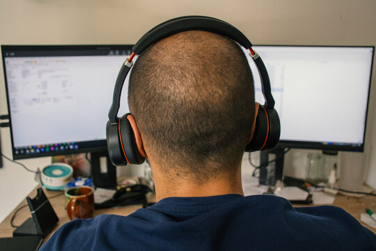 Man Working in Home Office with Headphones and Computer Monitors