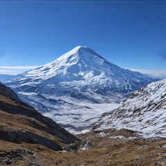 High mountain covered in snow, viewed from afar, with clear sky in the background