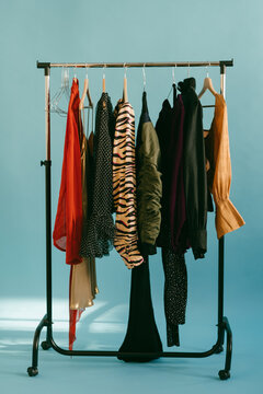 Clothing rack with a few dresses hanging on wooden hangers.