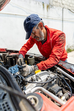 An experienced mechanic conducts maintenance on a vehicle's engine