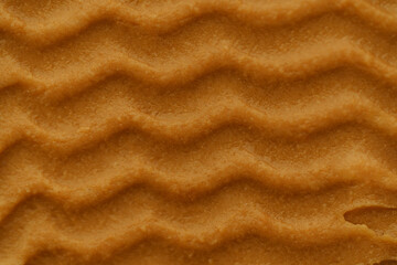 Smear texture of brown peanut paste close-up. Concept of protein snacks, natural sweets