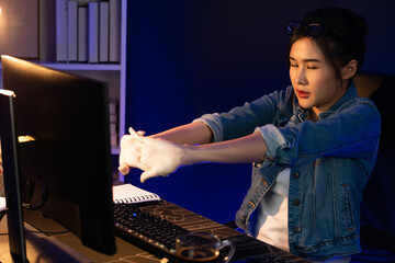 Young beautiful Asian businesswoman taking break with stretching body with ache symptom for relaxing muscle after finishing overworked load report at neon light modern office at night time. Stratagem.