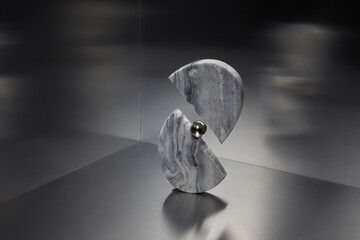 Reflective ball between two halves of stone marble figure