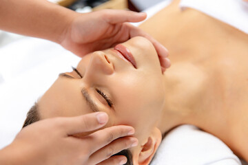 Closeup woman enjoying relaxing anti-stress head massage and pampering facial beauty skin recreation leisure in dayspa modern light ambient at luxury resort or hotel spa salon. Quiescent