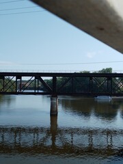 A large metal bridge over a reflecting river with a boat