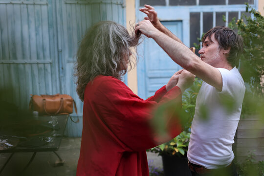Positive and extrovert hairdresser cutting hair in charming patio 