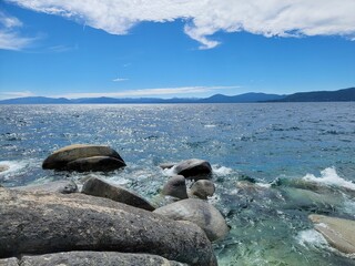Scenic view of Lake Tahoe with clear blue skies and rocks in the foreground.