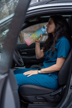 Nurse in driver seat of her car drinking water