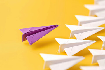 Fototapeta premium A striking image of a purple paper airplane standing out among white ones against a vibrant yellow background.