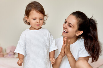 loving mother applauding to her cute baby girl in her room, support and motivation of the child