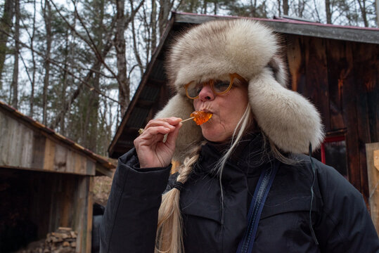 Senior happy woman eating a maple taffy in the woods