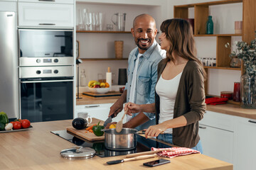 Happy beautiful couple cooking together in the kitchen at home
